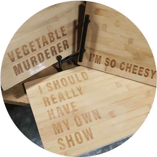 Three cutting or serving boards with sayings including Vegetable Murderer, Im so cheesey, and I should Have My Own Show.